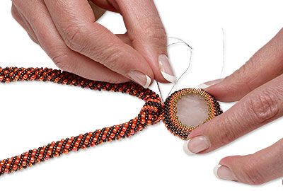 Putting the needle through the beads where the circle connects to the strip